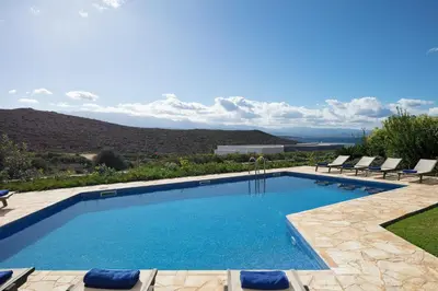 a swimming pool with chairs and a view of the mountains at Lake and Sea Villa in Tersanas