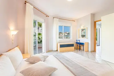 a bedroom with a large white bed and windows at Anna Αpartments II in Agia Marina Nea Kydonias