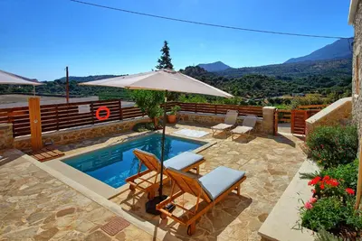 a swimming pool with chairs and an umbrella at Villa Vicilla by PosarelliVillas in Fílippos