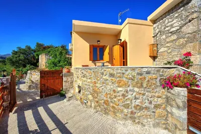 a house with a stone wall and a fence at Villa Vicilla by PosarelliVillas in Fílippos