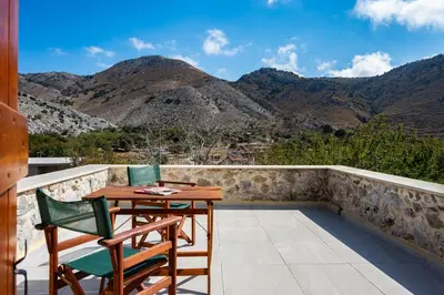 a balcony with a table and chairs and mountains at Archodiko Villa Imbros in Ímbros
