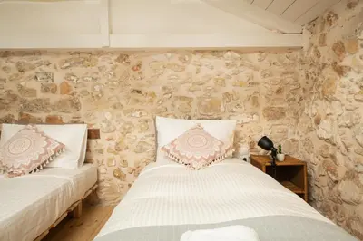 two beds in a room with a stone wall at Beit Petra in Daratso