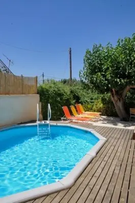 a swimming pool with a water fountain on a wooden deck at Sarris House in Xirokámbion