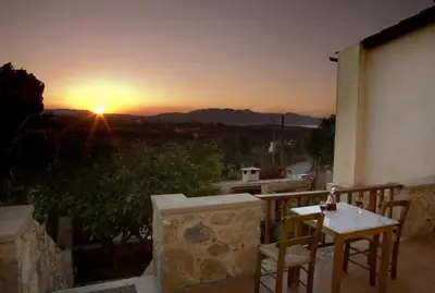 a table and chairs on a balcony with the sunset at Sarris House in Xirokámbion