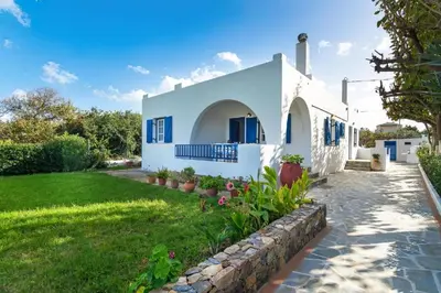 a white house with blue windows and a yard at Blue Beach House in Kissamos