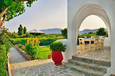an archway leading to a patio with a table and flowers at Blue Beach House in Kissamos
