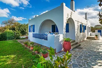 a white house with blue windows and potted plants at Blue Beach House in Kissamos