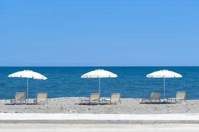 a group of chairs and umbrellas on the beach at Athina Luxury Villa, with Pool & Walk to the Beach, By ThinkVilla in Chania Town
