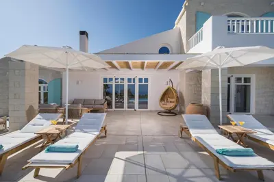 a patio with white lounge chairs and umbrellas at Villa Everlong in Vamos