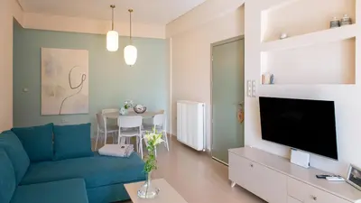 a living room with a blue couch and a tv at Happiness Luxury Home in Palaiochóra
