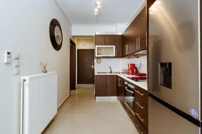 a kitchen with wooden cabinets and a clock on the wall at Lazaretta apartment in Chania Town