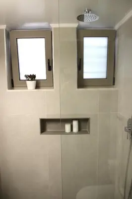 a bathroom with a shower and two windows and a toilet at New Cozy Chic Apt-Ryfete Luxury Living in Kalathas