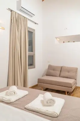 a room with a couch and two towels on a table at Fragios Beach House in Chania Town