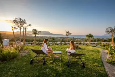 two women sitting on chairs in the grass at Villas Phos and Kallos in Kissamos