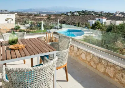 a balcony with a table and chairs and a pool at VILLA AMANTELLA in Stavros