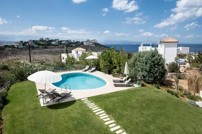 a pool with chairs and an umbrella in a yard at VILLA AMANTELLA in Stavros