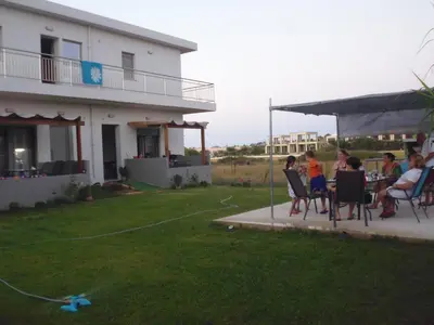 a group of people sitting at a table outside of a house at SEA BREEZE APARTMENTS in Kolymvari