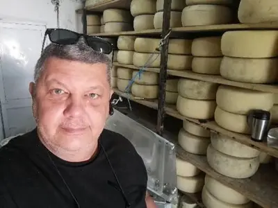 a man with sunglasses on his head in front of cheese racks at SEA BREEZE APARTMENTS in Kolymvari