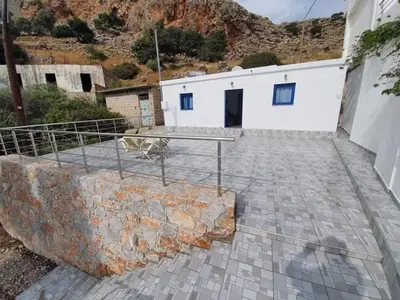 a white building with a fence and a stone wall at EDEM HOUSE FINIKAS in Loutro