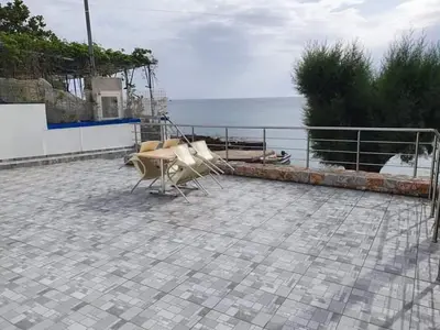 a group of chairs sitting on a patio near the ocean at EDEM HOUSE FINIKAS in Loutro