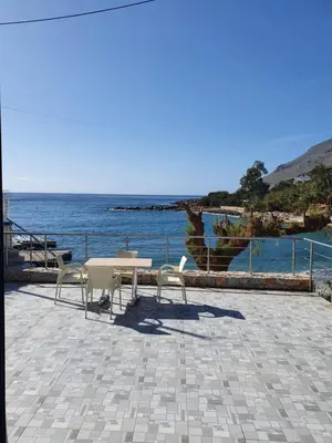 a table and chairs on a patio overlooking the ocean at EDEM HOUSE FINIKAS in Loutro