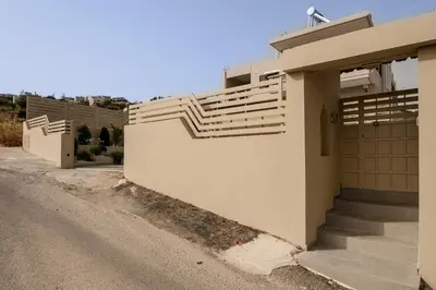 a house with a gate and stairs next to a road at Thyme Sea View Apartments by 8essentially in Souda