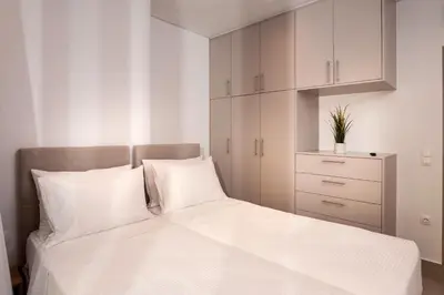 a bedroom with a white bed and white cabinets at Thyme Sea View Apartments by 8essentially in Souda