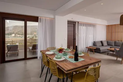 a living room with a wooden table and chairs at Thyme Sea View Apartments by 8essentially in Souda