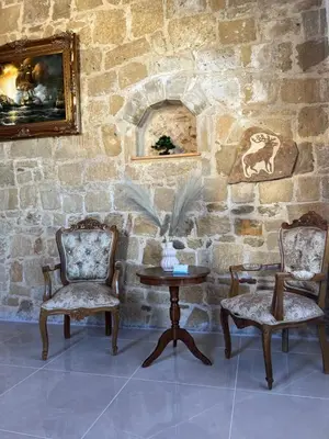 a room with two chairs and a table and a stone wall at Secret Garden Hotel in Maleme