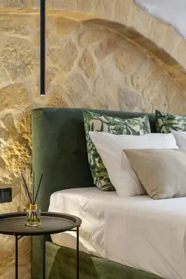 a bed with a table next to a stone wall at Monk Rooms in Chania Town