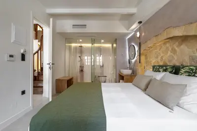 a bedroom with a large white bed and a bathroom at Monk Rooms in Chania Town