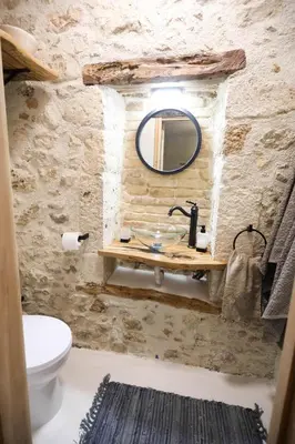 a bathroom with a sink and a mirror on a stone wall at Ravi Boutique Home - 1 minute walk from beach in Kalyves