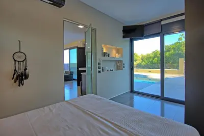 a bedroom with a bed and a view of a pool at Villa Maripol by PosarelliVillas in Galatás