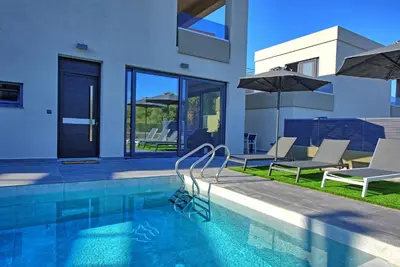 a swimming pool with two chairs and an umbrella at Villa Maripol by PosarelliVillas in Galatás