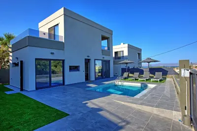 a white house with a swimming pool and some chairs at Villa Maripol by PosarelliVillas in Galatás