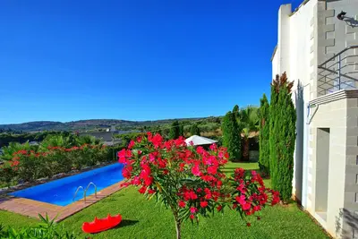 a garden with red flowers and a swimming pool at Villa Politini by PosarelliVillas in Vryses