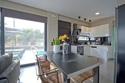 a kitchen and living room with a table and chairs at Villa Popi - modern villa with private pool by PosarelliVillas in Galatás