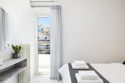 a white bedroom with a bed and a window at West City Apartment in Chania Town