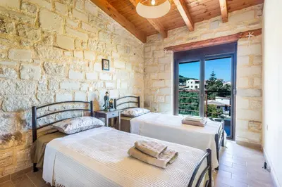 two beds in a room with a stone wall at SpiliaInn in Spiliá