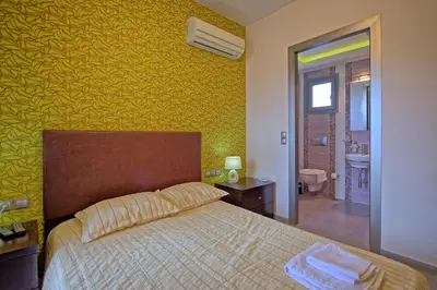 a bedroom with a bed and a yellow wall at Cabanavillas Casablanca by PosarelliVillas in Plaka