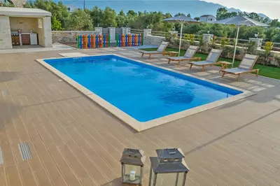 a large blue swimming pool with chairs and a playground at Villa Despanto by PosarelliVillas in Litsárdha
