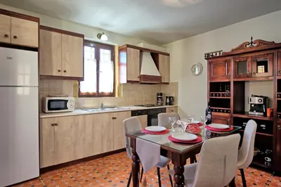 a kitchen with a table and chairs and a white refrigerator at Villa Sevi Grande by PosarelliVillas in Káto Vení