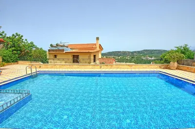 a large swimming pool with a house in the background at Villa Sevi Grande by PosarelliVillas in Káto Vení
