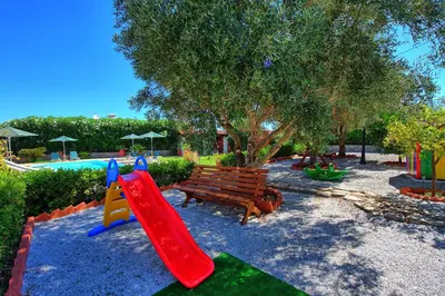 a playground with a wooden bench and a slide at Villa Antina by PosarelliVillas in Litsárdha