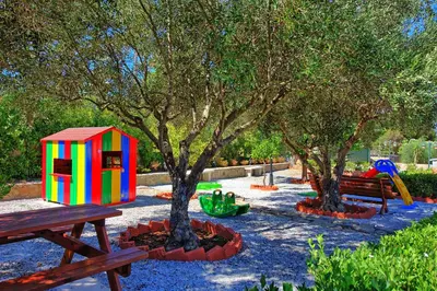 a park with trees and a playground with benches at Villa Antina by PosarelliVillas in Litsárdha