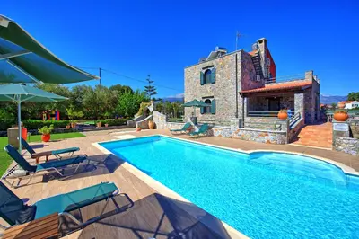 a villa with a swimming pool in front of a house at Villa Antina by PosarelliVillas in Litsárdha
