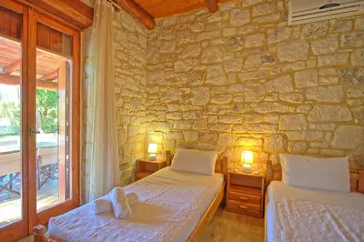 a bedroom with two beds and a stone wall at Villa Vrisses by PosarelliVillas in Vryses