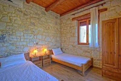 a bedroom with two beds and a window in a stone wall at Villa Nipos by PosarelliVillas in Vryses