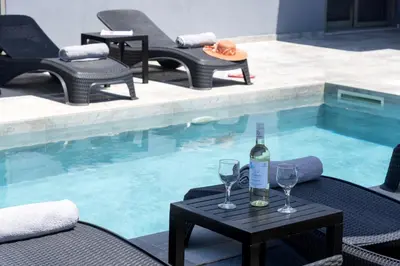 a bottle of wine on a table next to a swimming pool at Villa Ampela by PosarelliVillas in Agia Marina Nea Kydonias