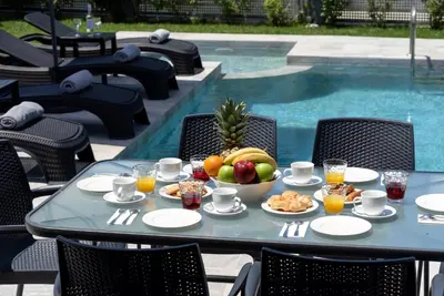 a table with a bowl of fruit next to a pool at Villa Ampela by PosarelliVillas in Agia Marina Nea Kydonias